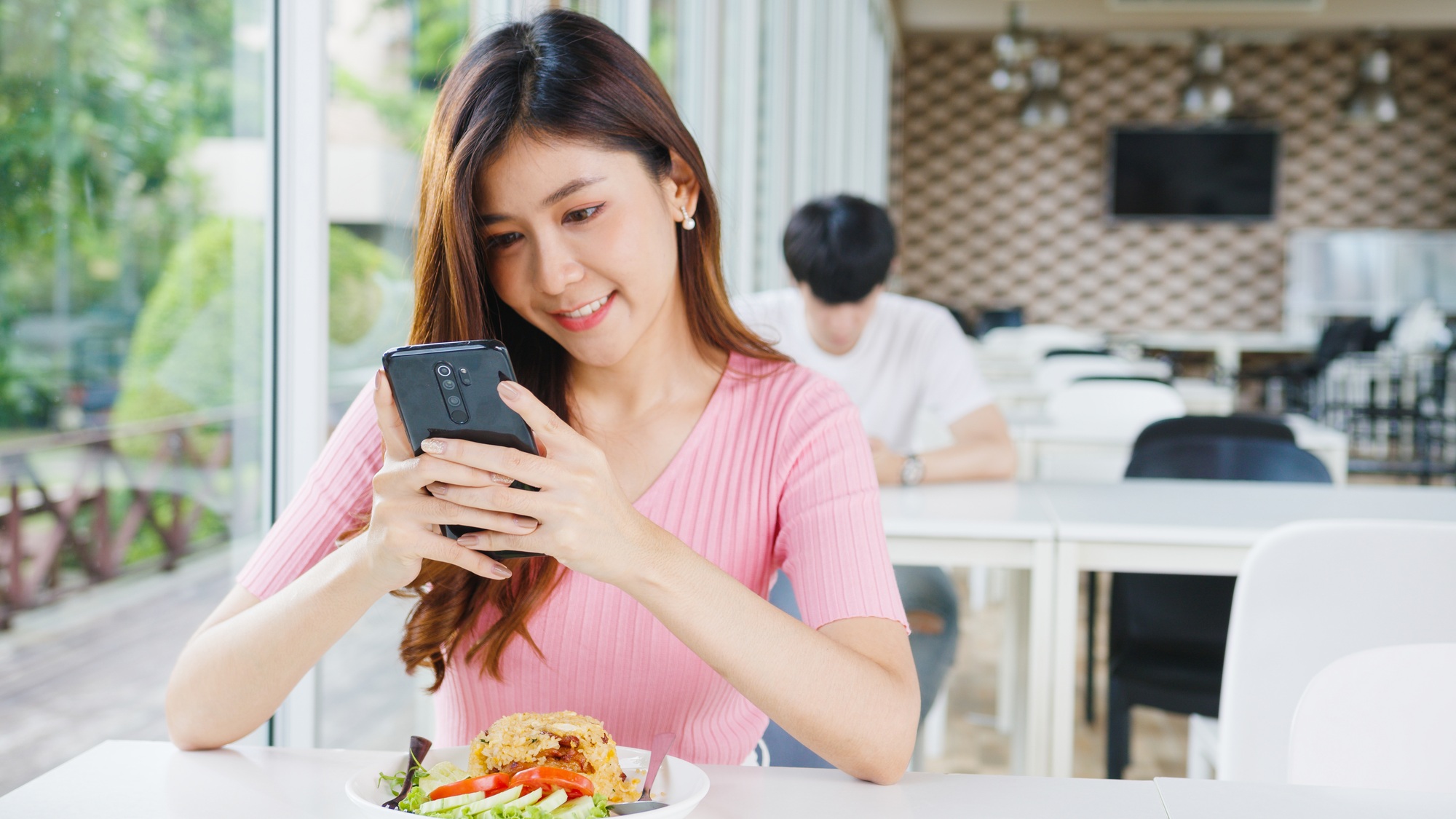 Young Asia female influencer food blogger taking photo of fried rice on smartphone.