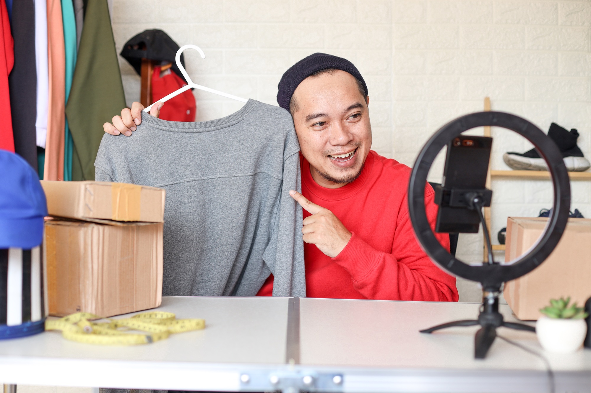 Young Asian influencer reviewing clothes on a live streamning